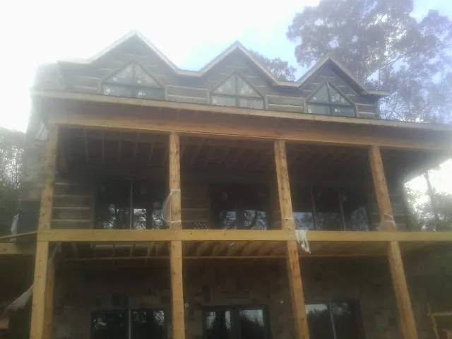 Dormers and porch framing on a large log home under construction — Roof Coating work by our crew in Urbana