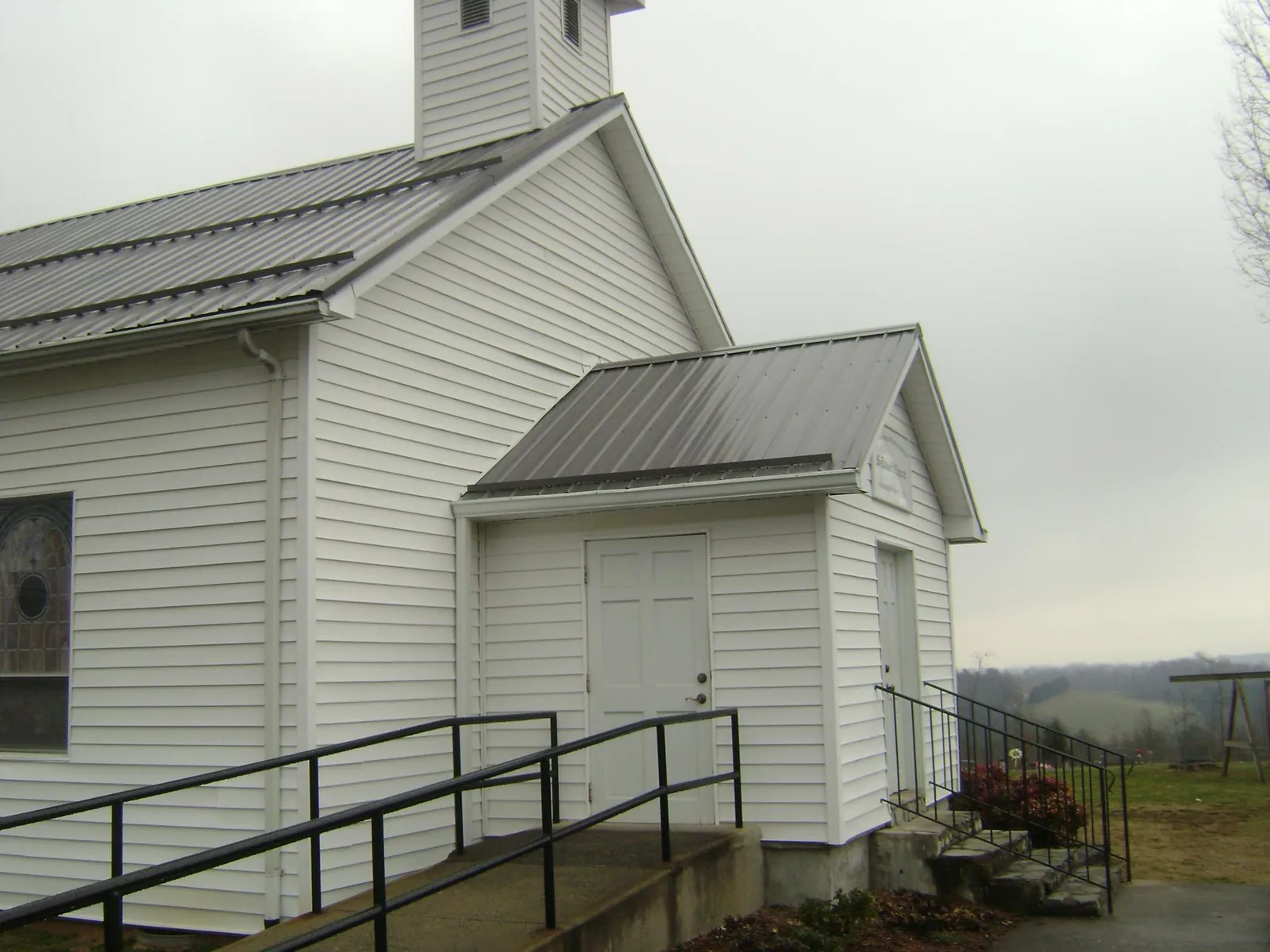Gray metal roof on a white clapboard church with a steeple in Urbana